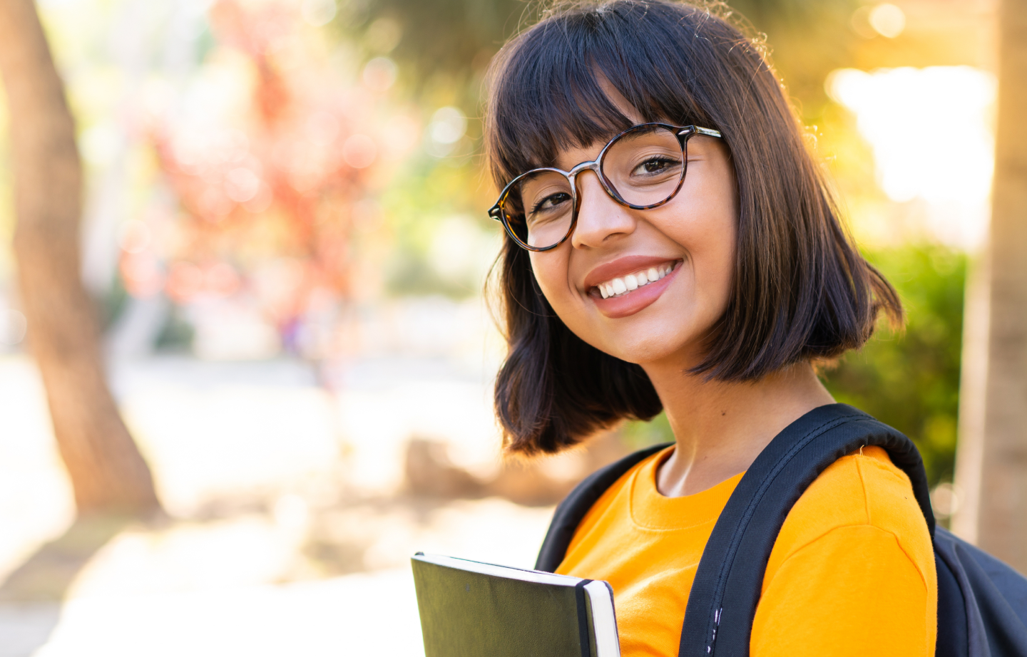 Estudante sorrindo com mochila e caderno